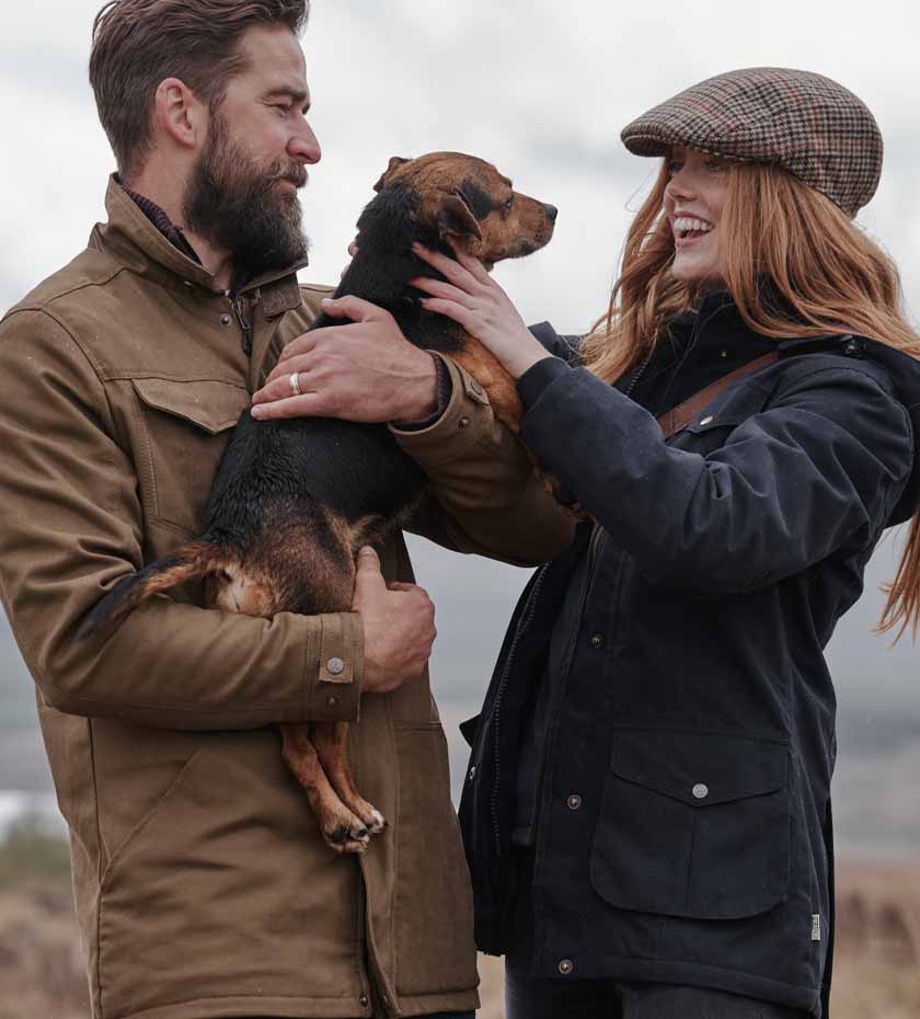 Man and woman in hoggs country clothing play with dog. Hoggs SALE.