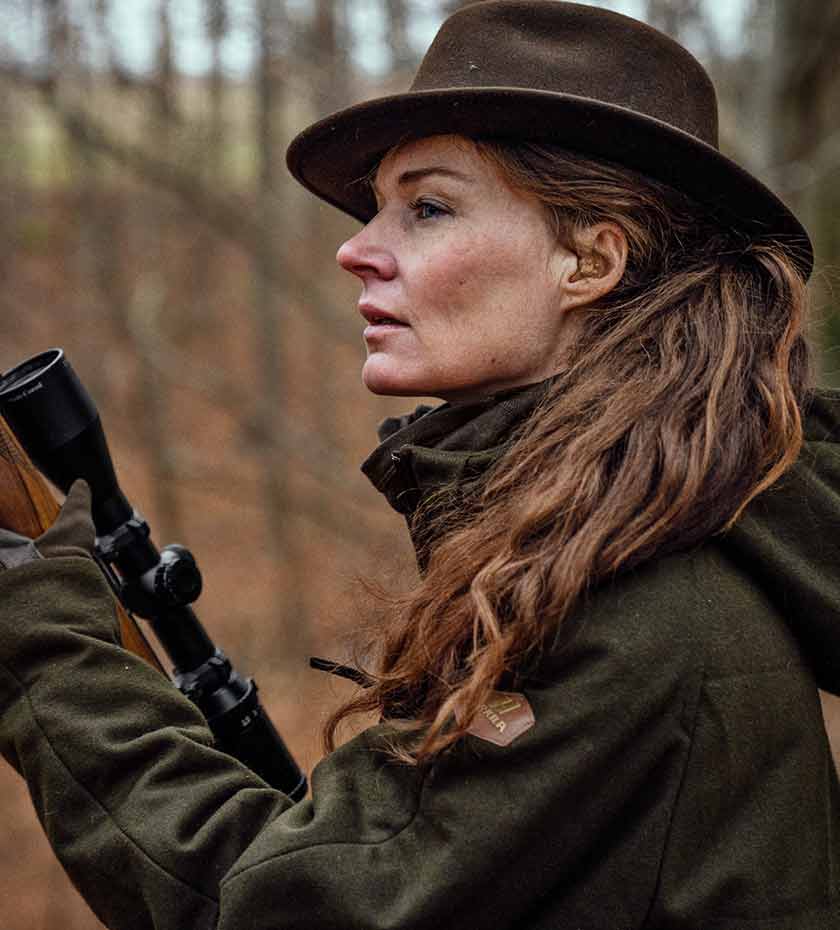Women's wearing Harkila jacket and hat in green for shooting and hunting.