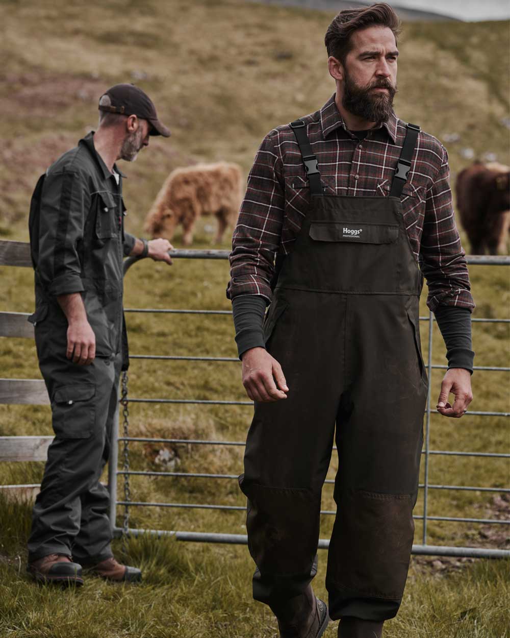 Two farmers with cattle in the background wearing hoggs professional agricultural workwear