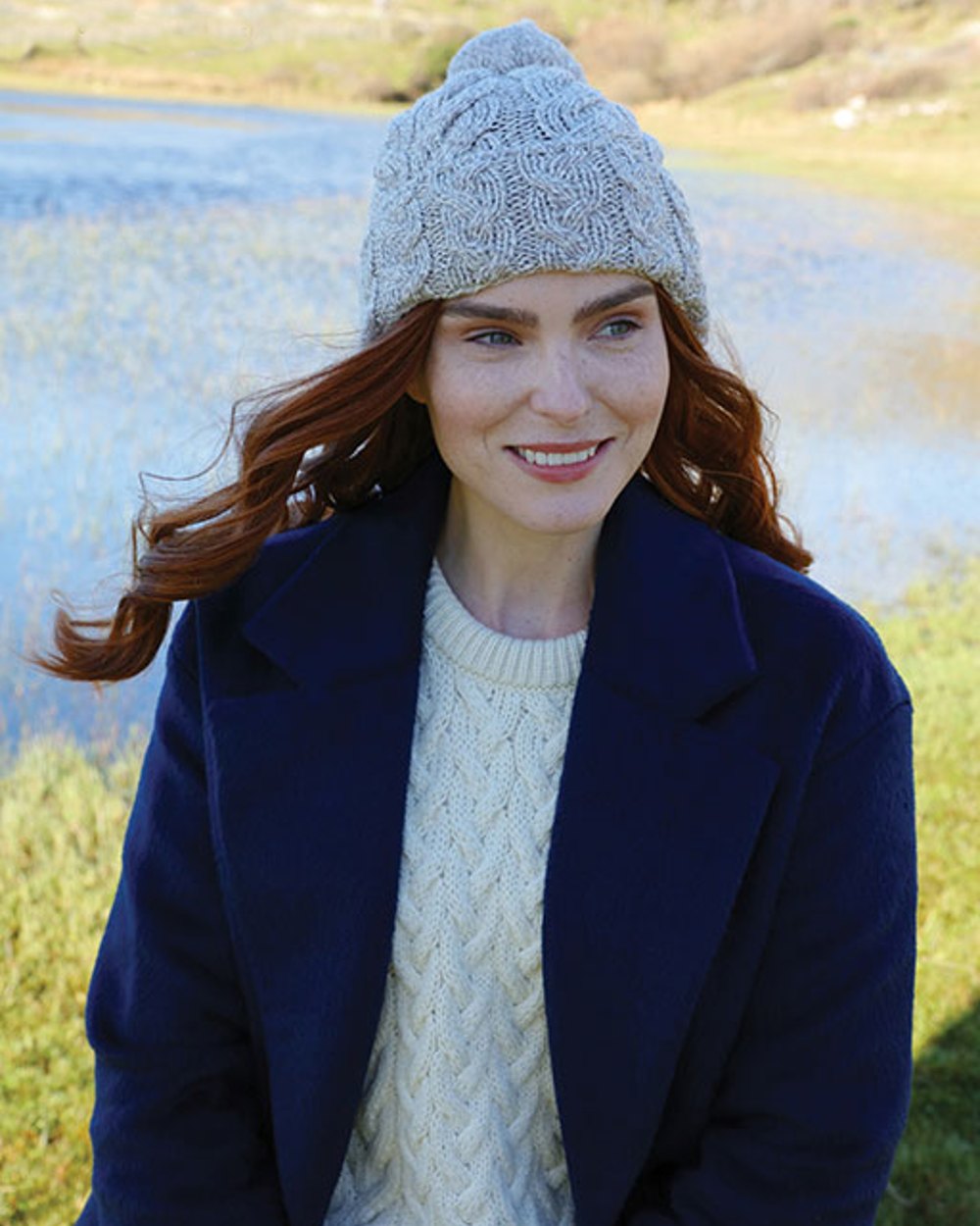 Light Grey Coloured Aran Chunky Knit Bobble Hat on lake background