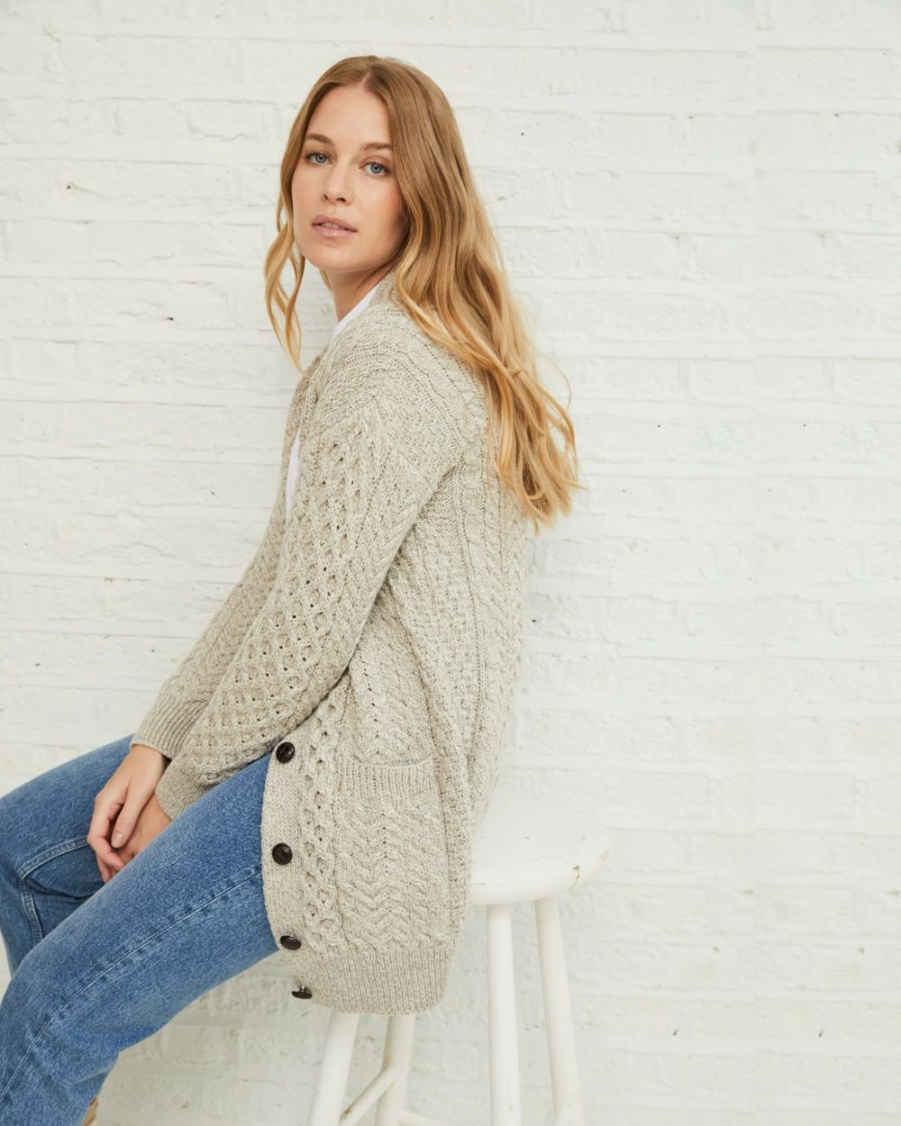 Oat Coloured Aran Delphi Boyfriend Cardigan on grey wall background