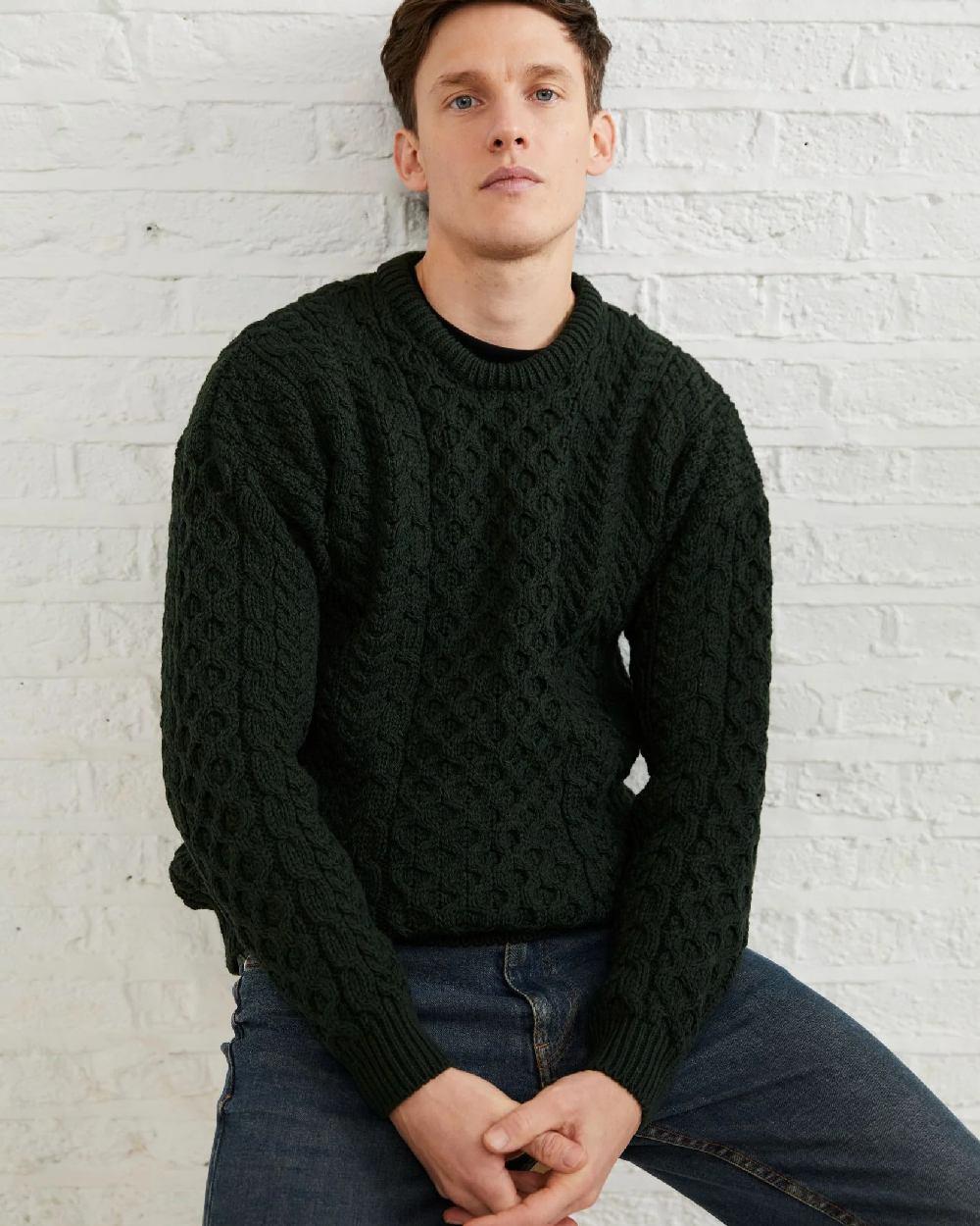 Forest Green Coloured Aran Inisheer Traditional Sweater on grey wall background