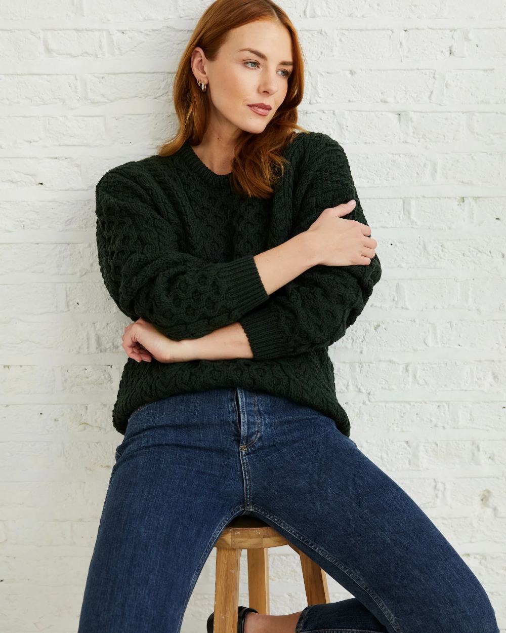Forest Green Coloured Aran Inisheer Traditional Sweater on grey wall background