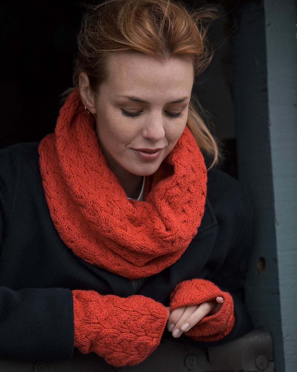 Coral Coloured Aran Supersoft Merino Fingerless Gloves on window background