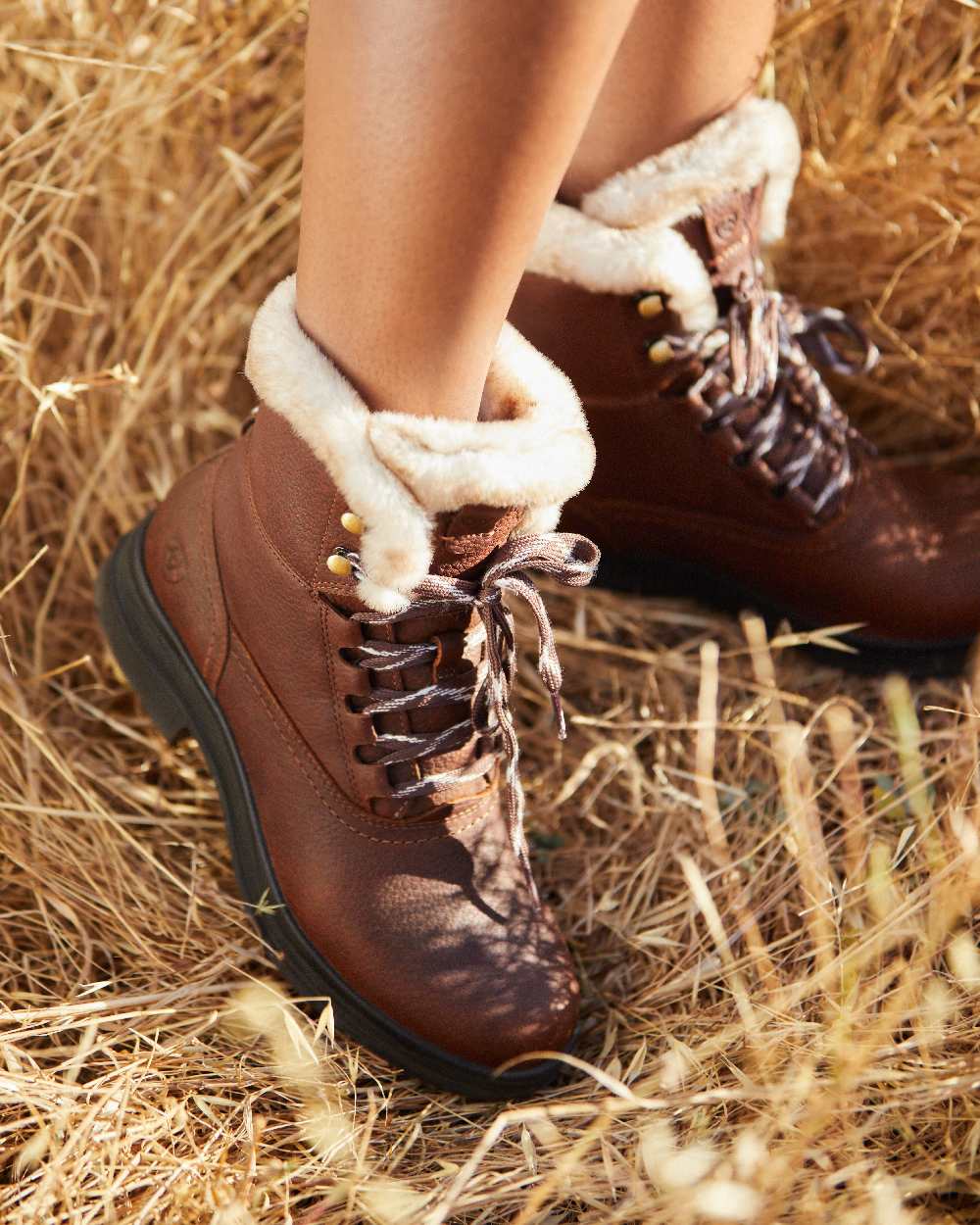 Dark Brown coloured Ariat Womens Harper Sherpa Waterproof Boots on hay background