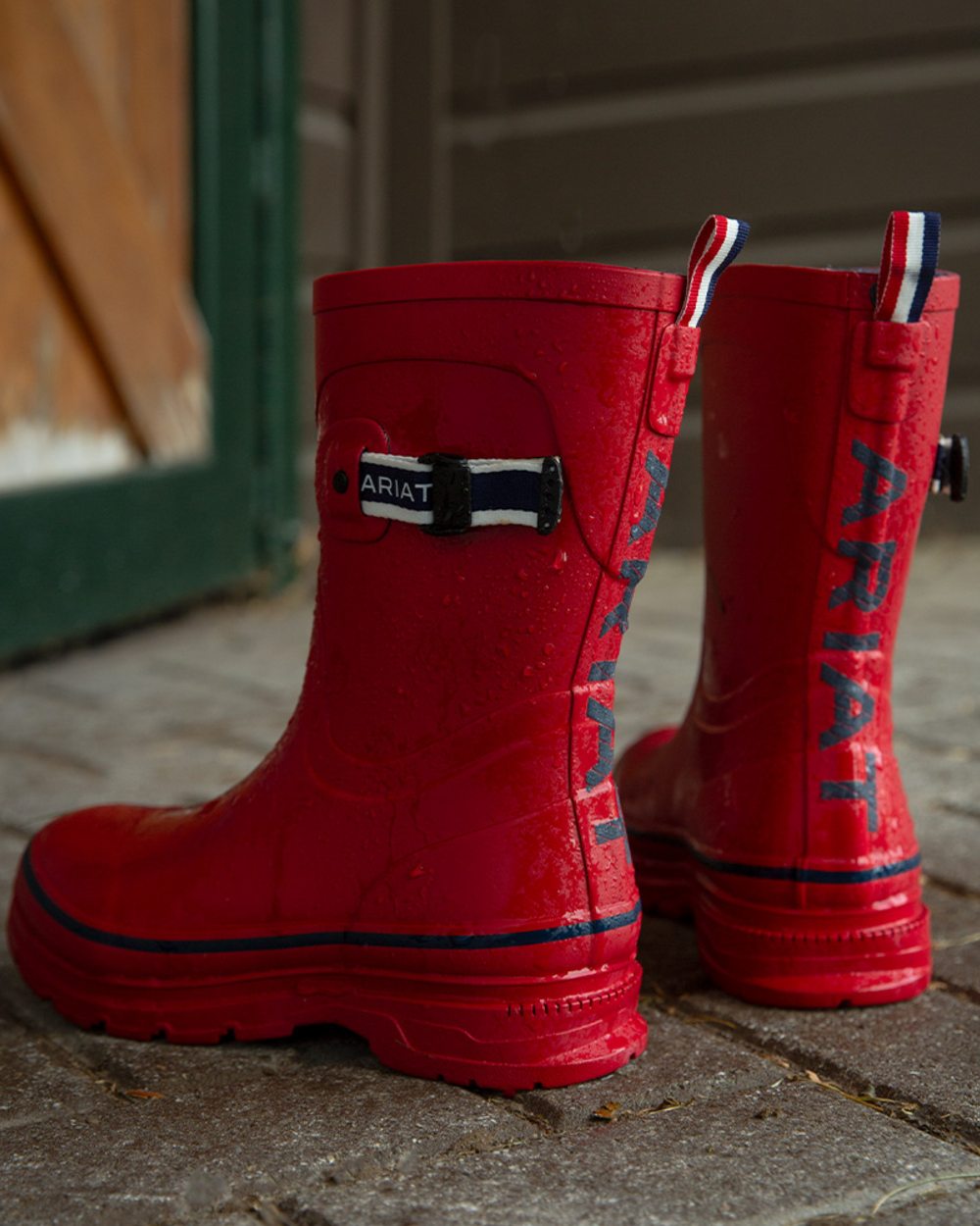 Team Red coloured Ariat Womens Kelmarsh Shortie Rubber Boots on outdoor background