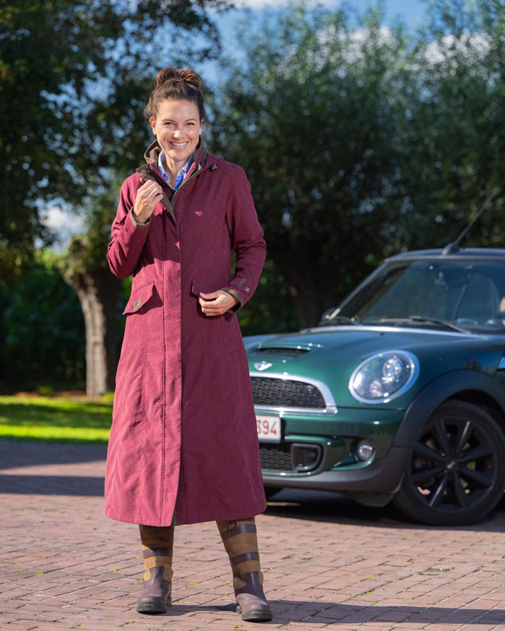 Raspberry Coloured Baleno Kensington Long Waterproof Coat on countryside background
