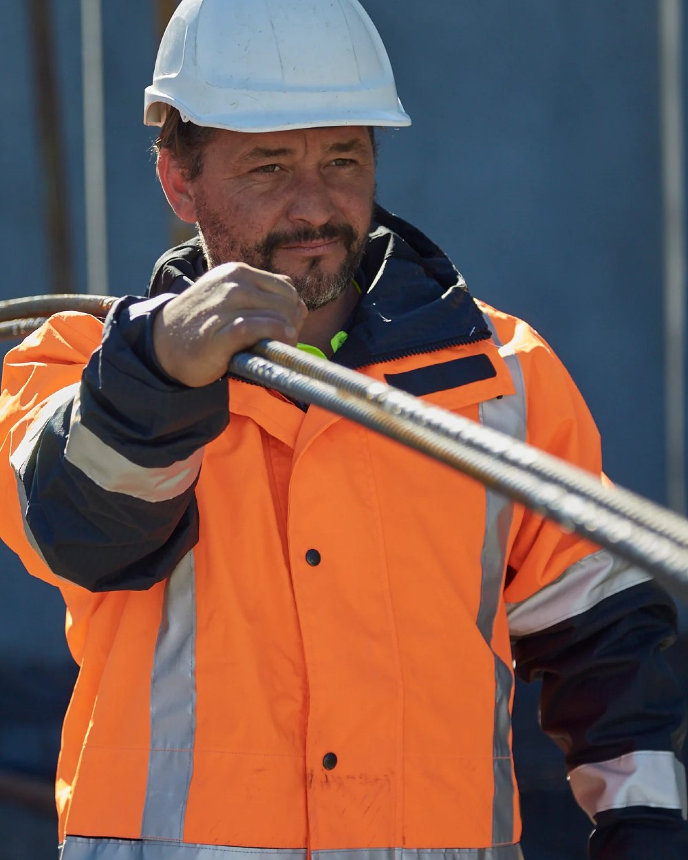 Fluoro Orange Navy coloured Betacraft ISO940 Waterproof Ranger Parka on factory background