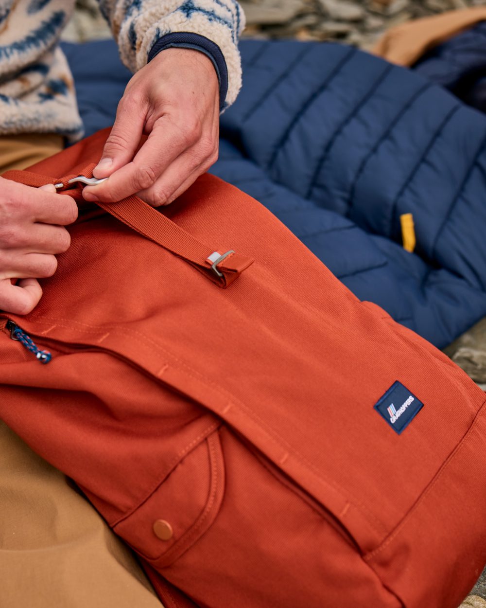 Red Beach coloured Craghoppers 20L Kiwi Classic Rolltop Backpack II on outdoor background