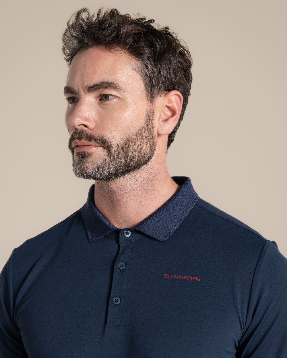 Blue Navy Coloured Craghoppers Mens Nosilife Bramshaw Short Sleeved Polo Top on Beige Background