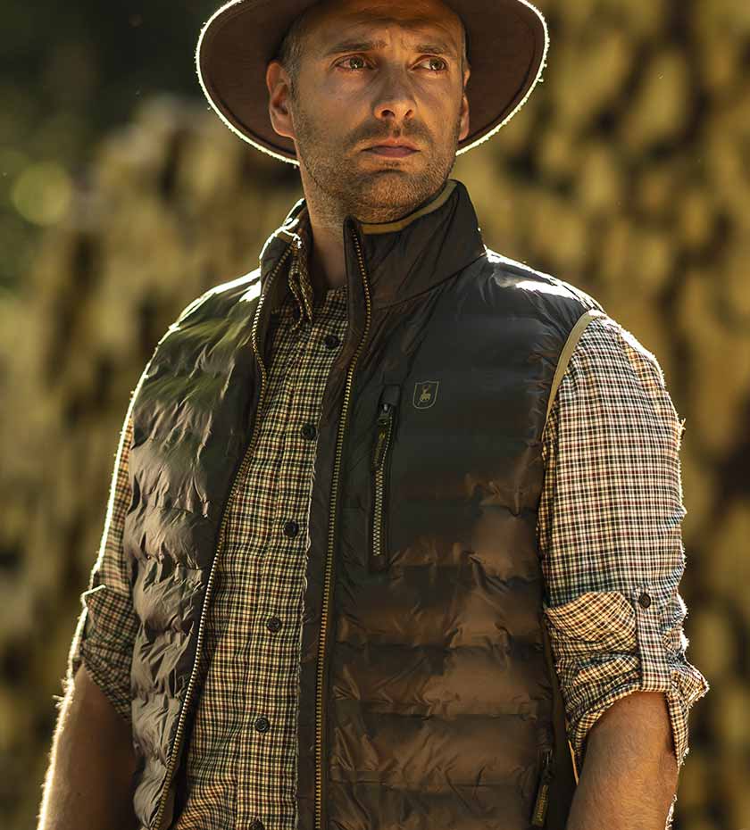 MAn wears Deerhunter quilted padded gilet over a check shirt.