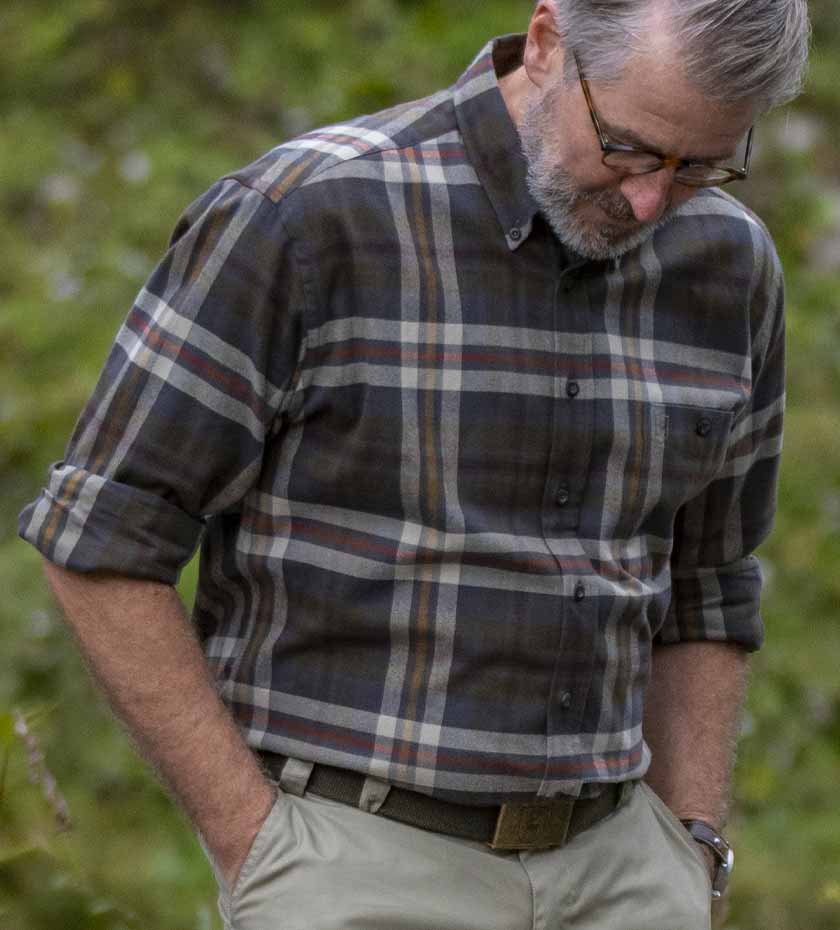 Man wears green tartan check Deerhunter long sleeved shirt.
