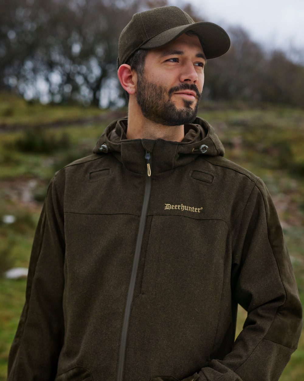 Loden Wood Coloured Deerhunter Tatra Jacket On A Forest Background
