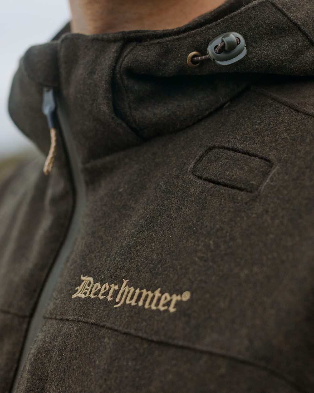 Loden Wood Coloured Deerhunter Tatra Jacket On A Forest Background
