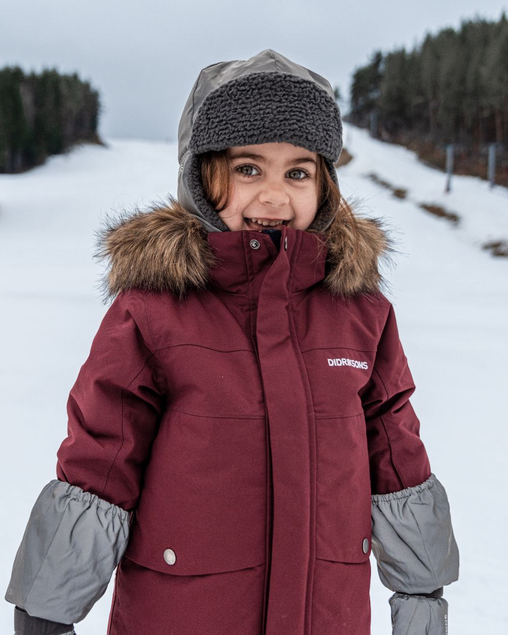 Silver coloured Didriksons Childrens Biggles Reflective Cap on snow background