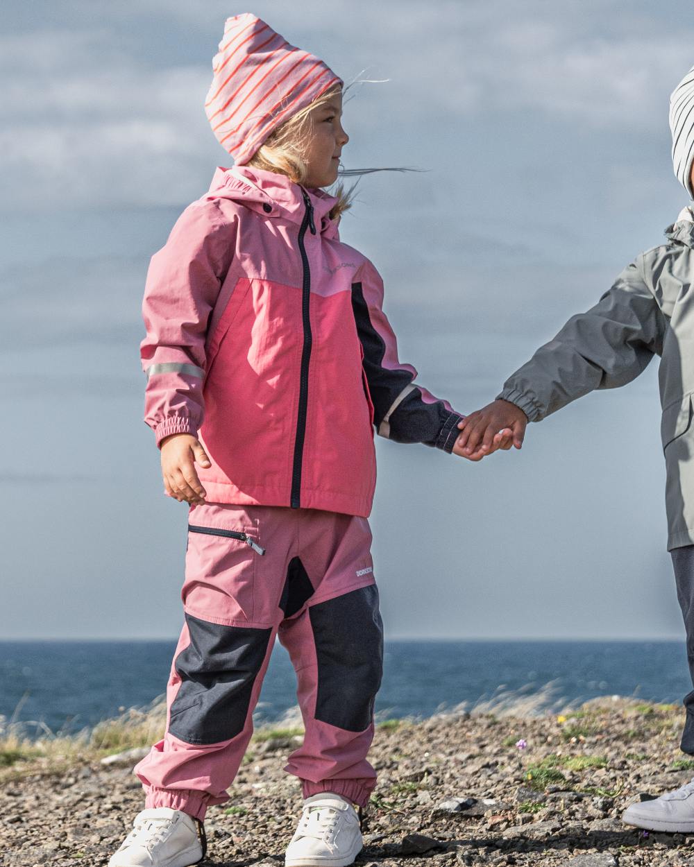 Heather Pink coloured Didriksons Childrens Dusk Pants on sea background