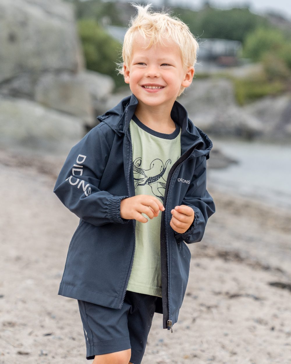 Navy coloured Didriksons Childrens Hallon Jacket on beach background