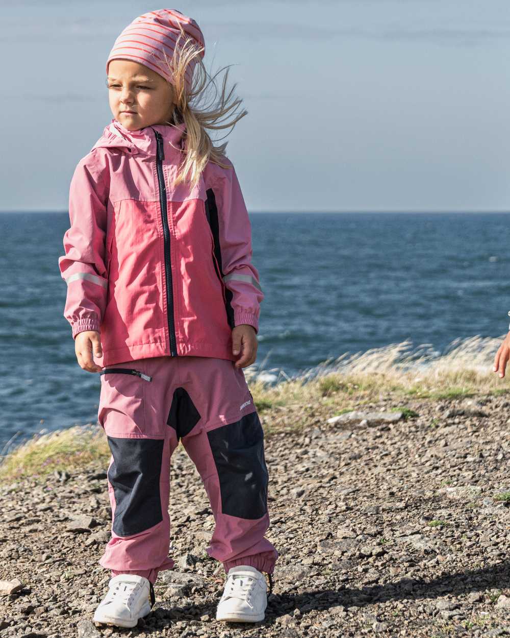 Heather Pink coloured Didriksons Childrens Pilvi Waterproof Jacket on sea background