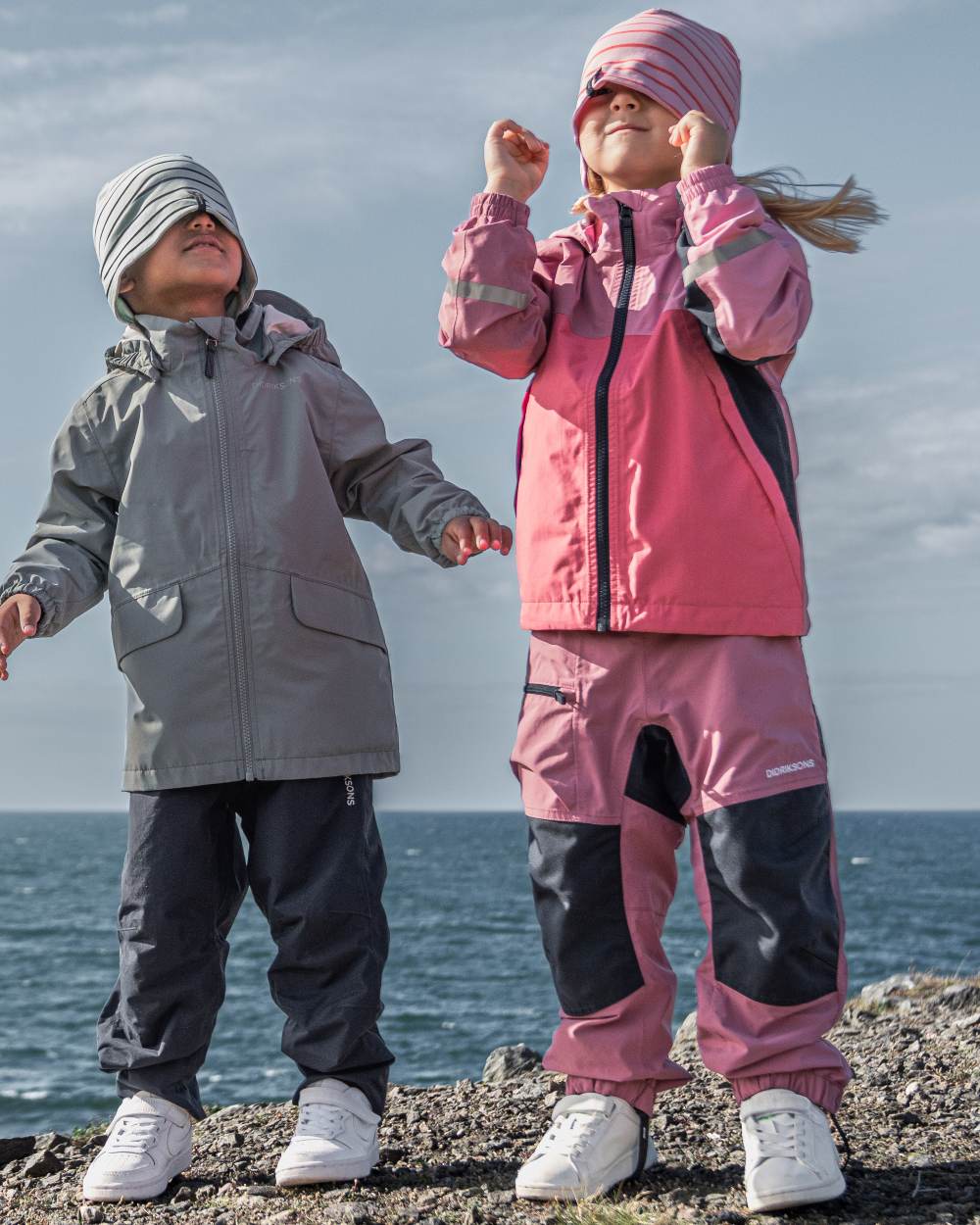 Heather Pink coloured Didriksons Childrens Pilvi Waterproof Jacket on sea background