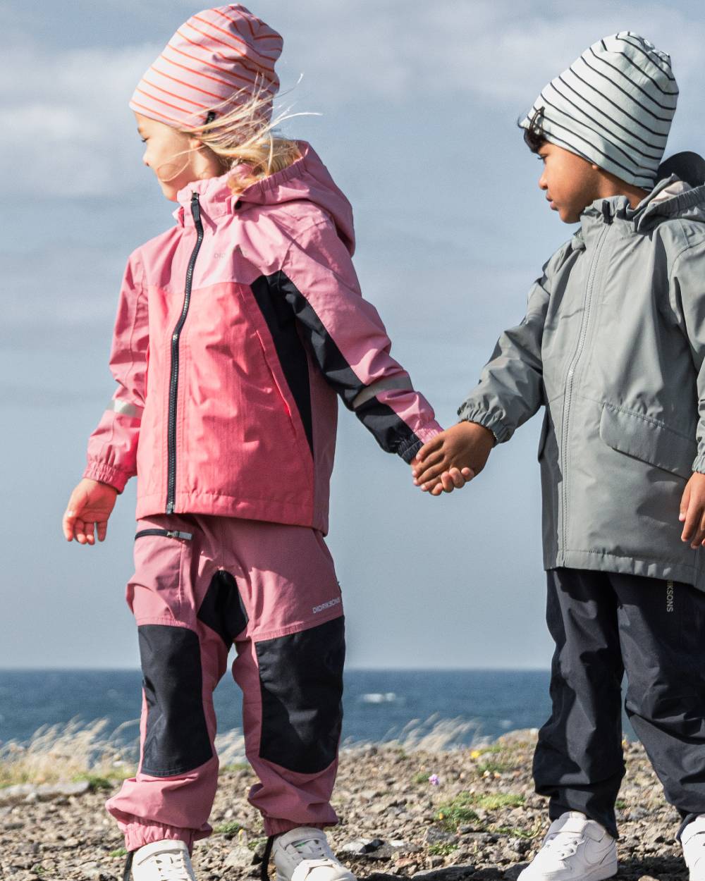 Heather Pink coloured Didriksons Childrens Pilvi Waterproof Jacket on sea background