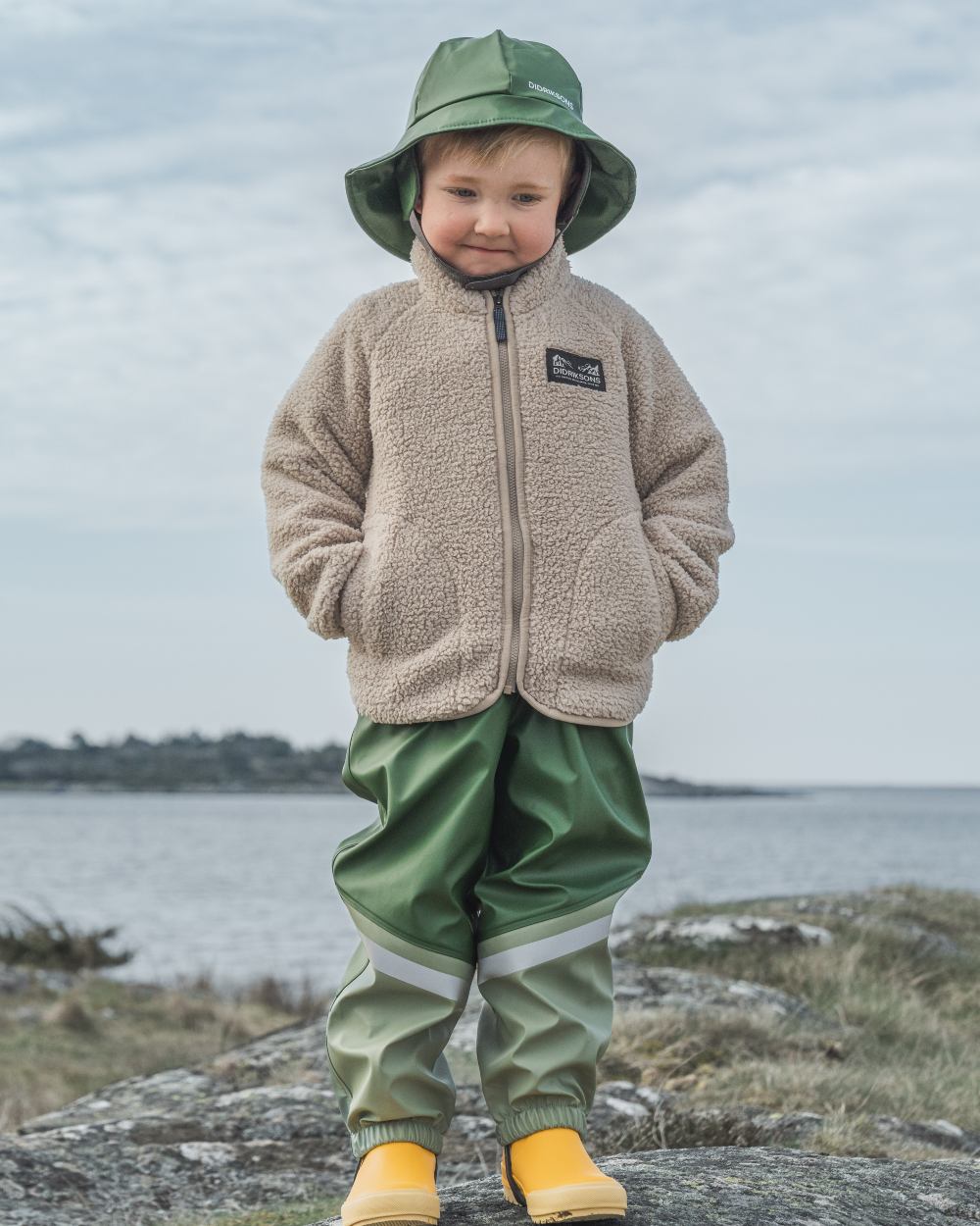 Pine Green coloured Didriksons Southwest Kids Galon on sea background