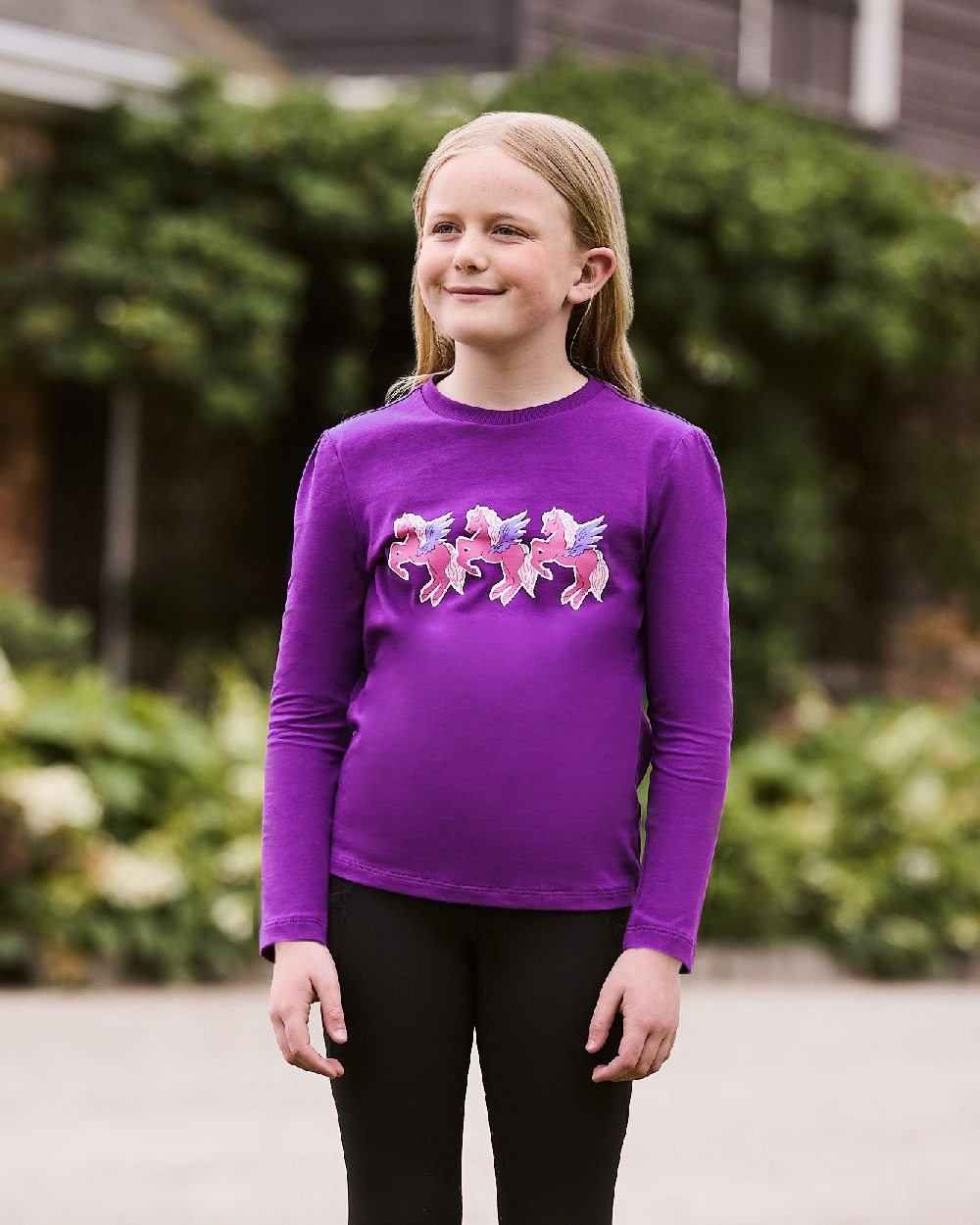 Imperial Purple Winged Ponies coloured Dublin Childrens Poppy Puff Sleeve Tee on blurry background