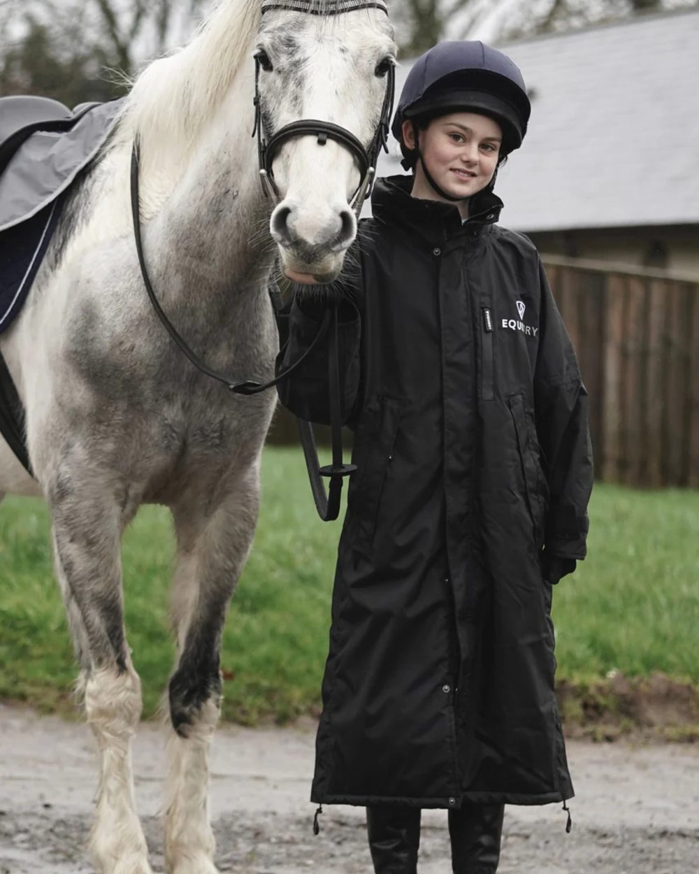 Black coloured Equidry Children Pro Ride Evolution Thin Fleece With Stowaway Hood on farm background