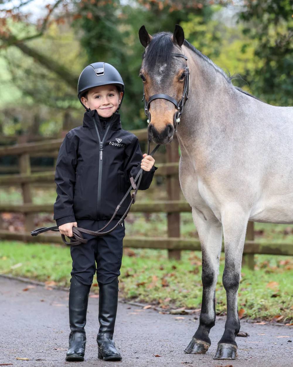 Black coloured Equidry Childrens Nimbus Pack Away Jacket With Stowaway Hood on outdoor background