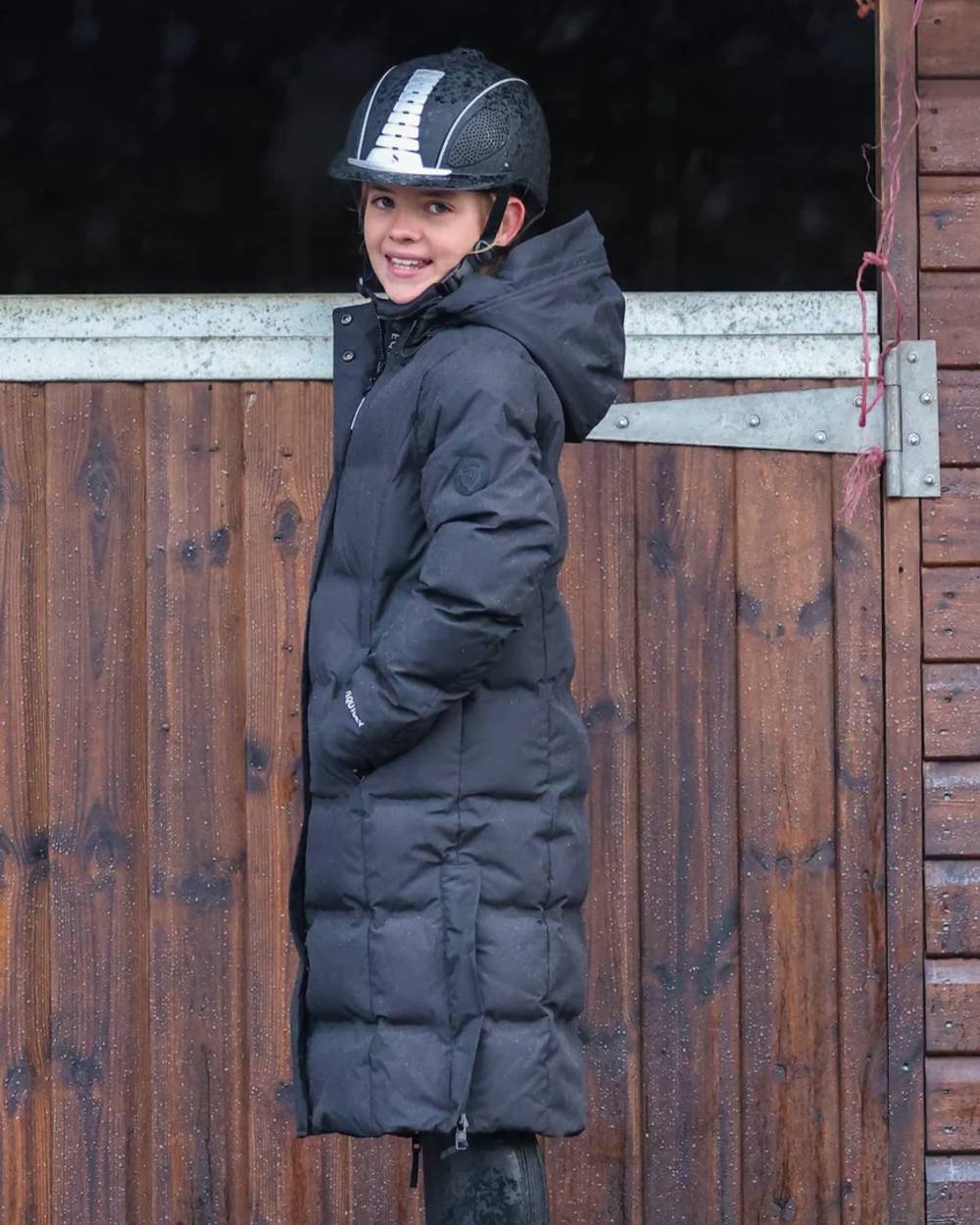 Black coloured Equidry Childrens Thora Waterproof Riding Puffer Jacket With Hood on stable background