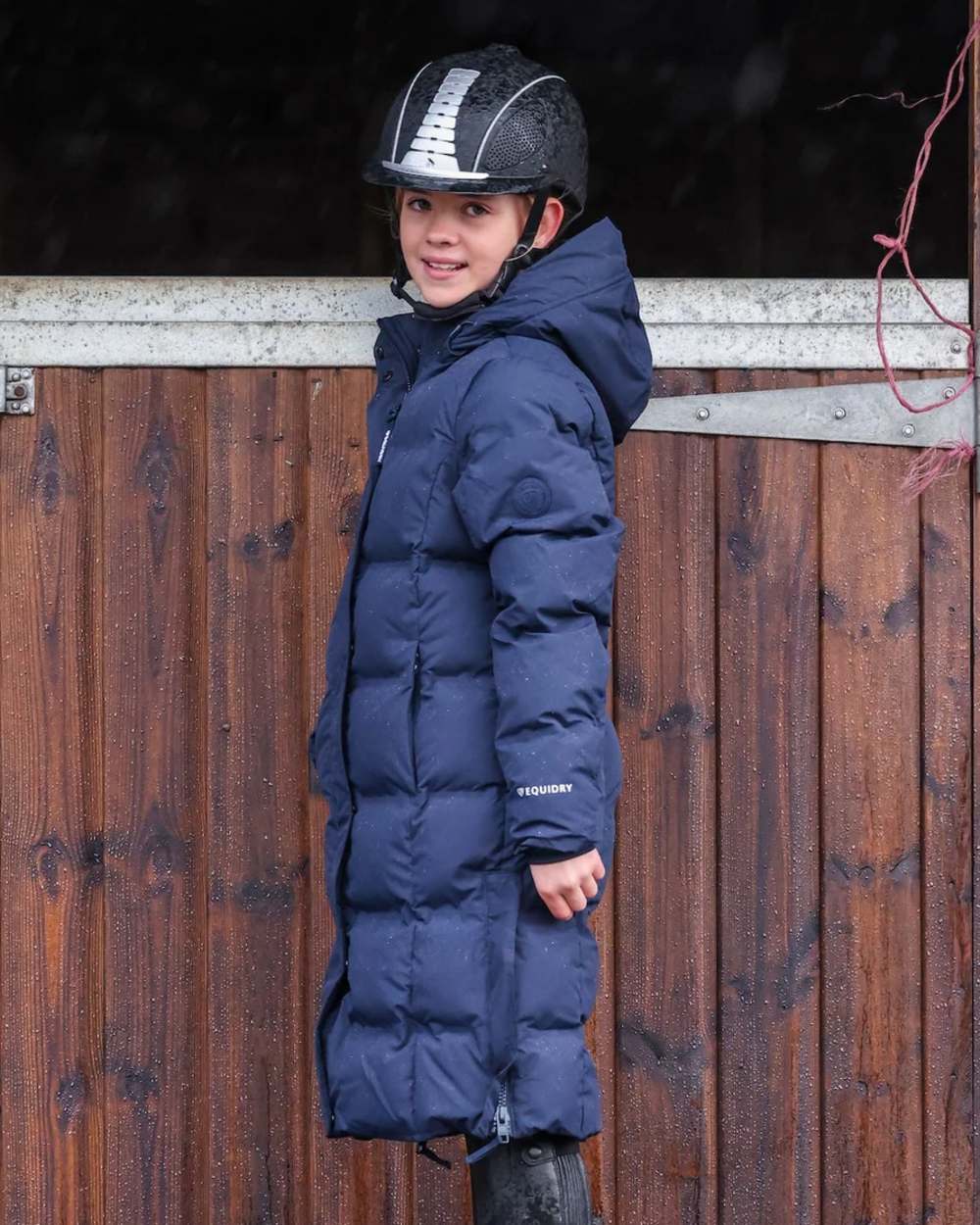 Navy coloured Equidry Childrens Thora Waterproof Riding Puffer Jacket With Hood on stable background