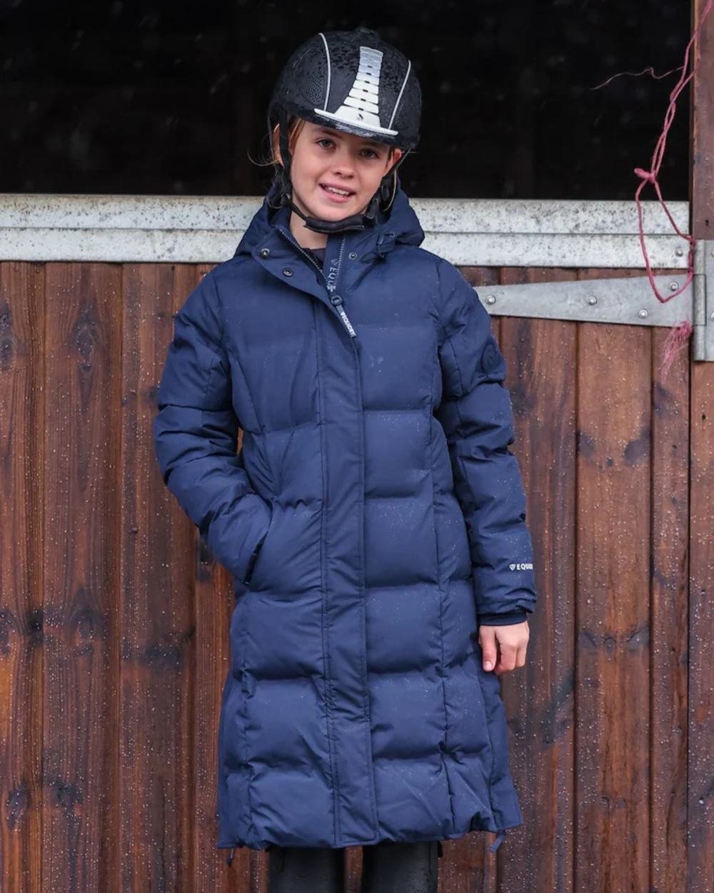 Navy coloured Equidry Childrens Thora Waterproof Riding Puffer Jacket With Hood on stable background