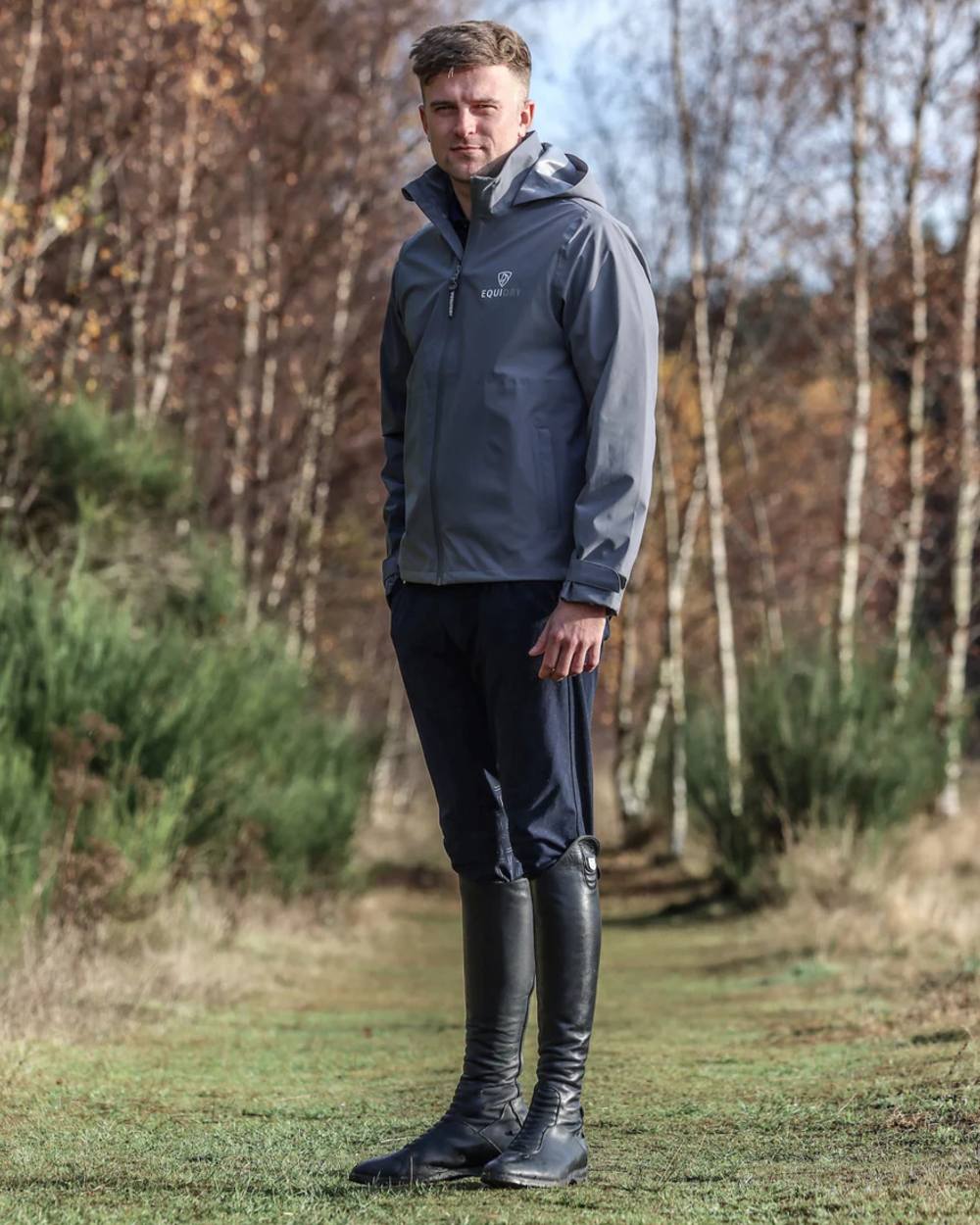 Charcoal coloured Equidry Mens Nimbus Pack Away Jacket With Stowaway Hood on forest background