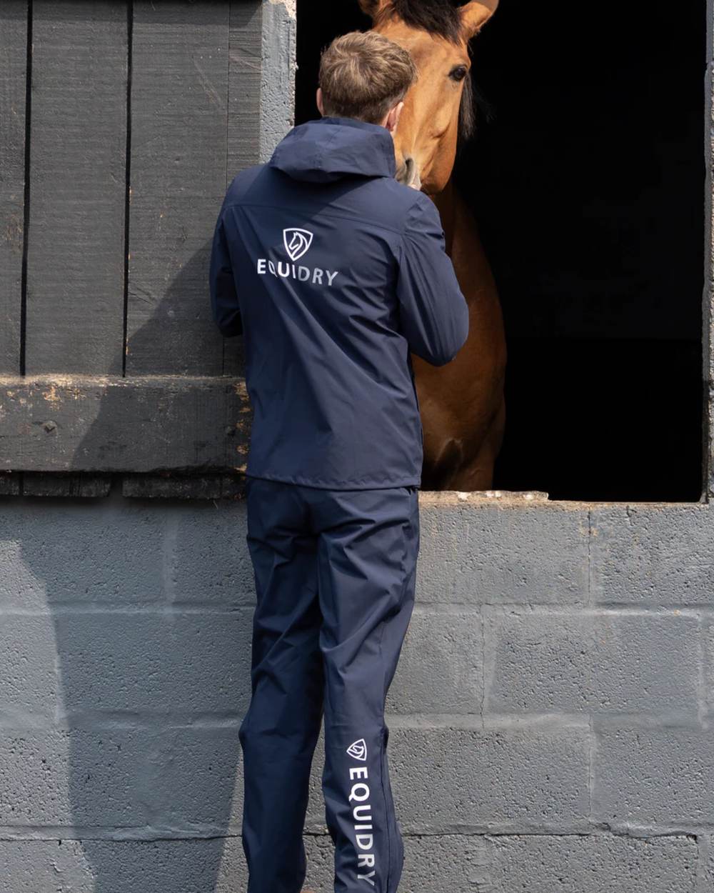 Navy coloured Equidry Mens Nimbus Pack Away Jacket With Stowaway Hood on outdoor background