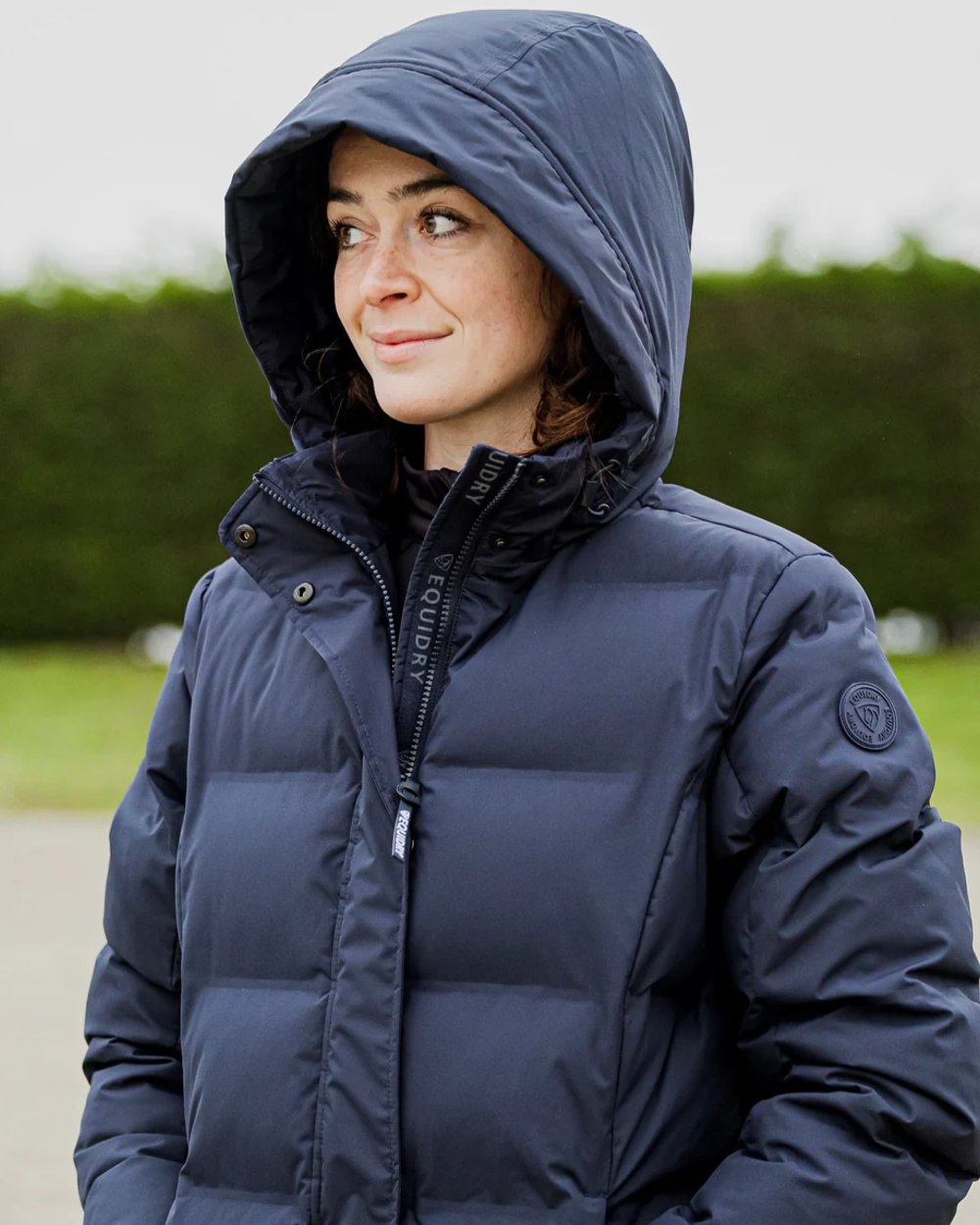 Navy coloured Equidry Thora Waterproof Riding Puffer Coat With Hood on outdoor background