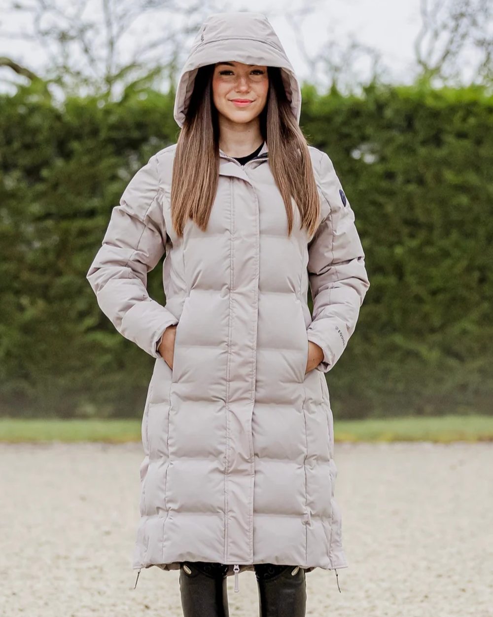 Taupe coloured Equidry Thora Waterproof Riding Puffer Coat With Hood on outdoor background