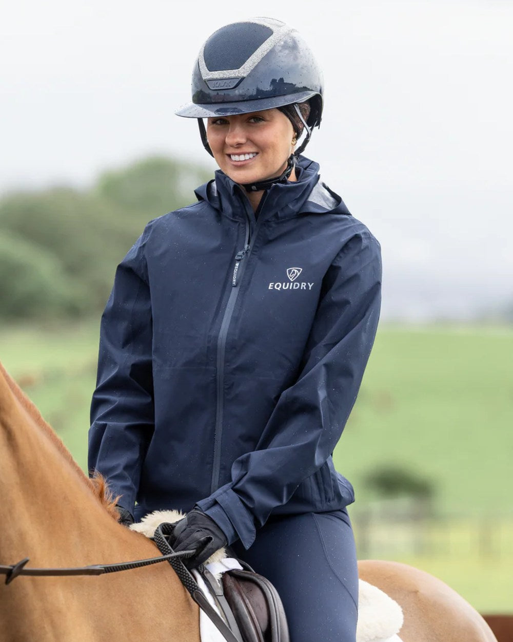 Navy coloured Equidry Womens Nimbus Pack Away Jacket with Stowaway Hood on blurry background