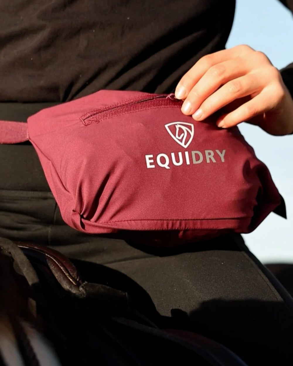 Plum coloured Equidry Womens Nimbus Pack Away Jacket with Stowaway Hood on outdoor background