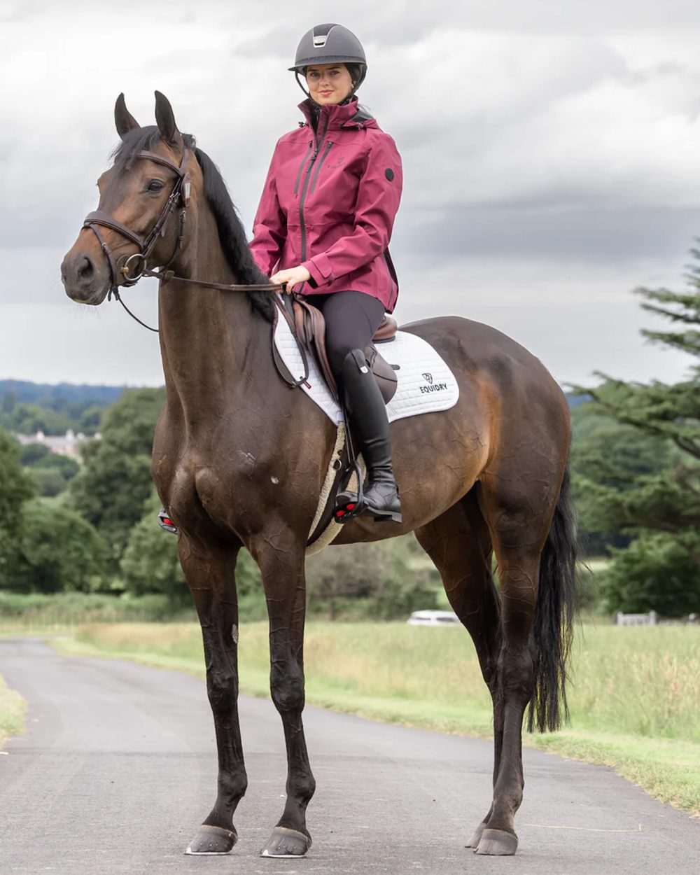 Plum coloured Equidry Womens Varsha Jacket with Stowaway Hood on street background