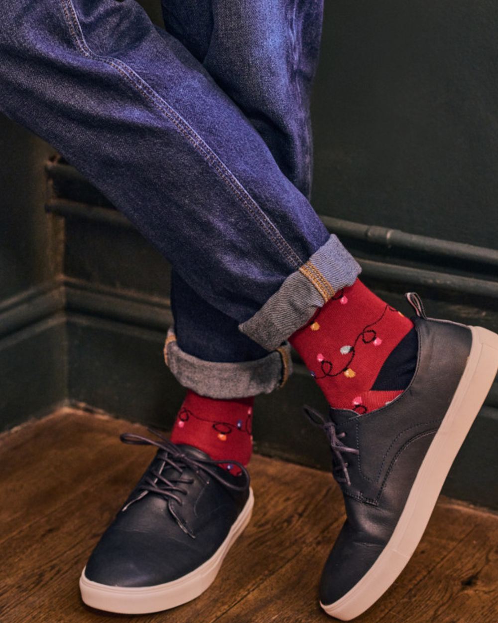 Red coloured HJ Hall Mens Christmas Lights Motif Cotton Rich Socks on indoor background