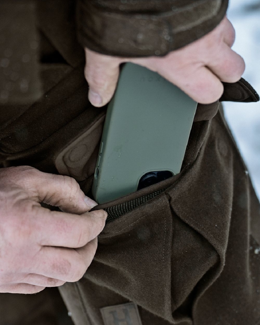 Dark Hunting Green Shadow Brown coloured Harkila Kodiak CleverWool HSP Insulated Trousers on winter background