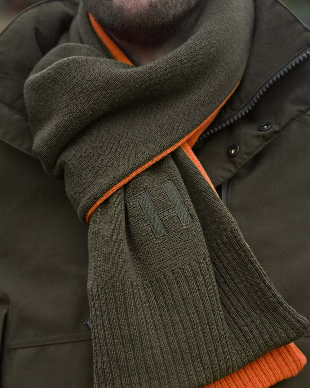 Willow Green Orange Coloured Harkila Reversible Scarf on outdoor background