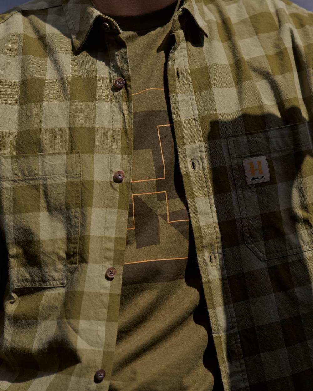 Dark Olive Check Coloured Harkila Scandinavian Long Sleeve Shirt on blurry background