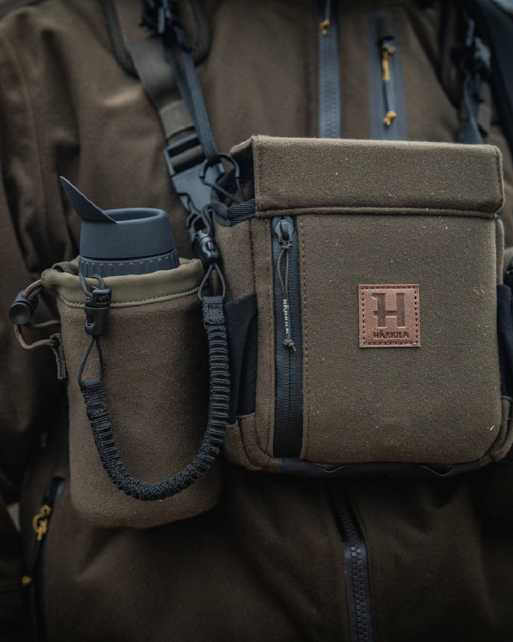 Dark Willow Green Coloured Harkila Thermal Spotter Pouch on blurry background