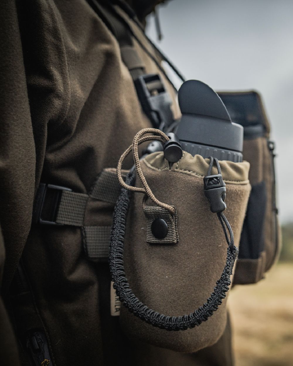 Dark Willow Green Coloured Harkila Thermal Spotter Pouch on blurry background