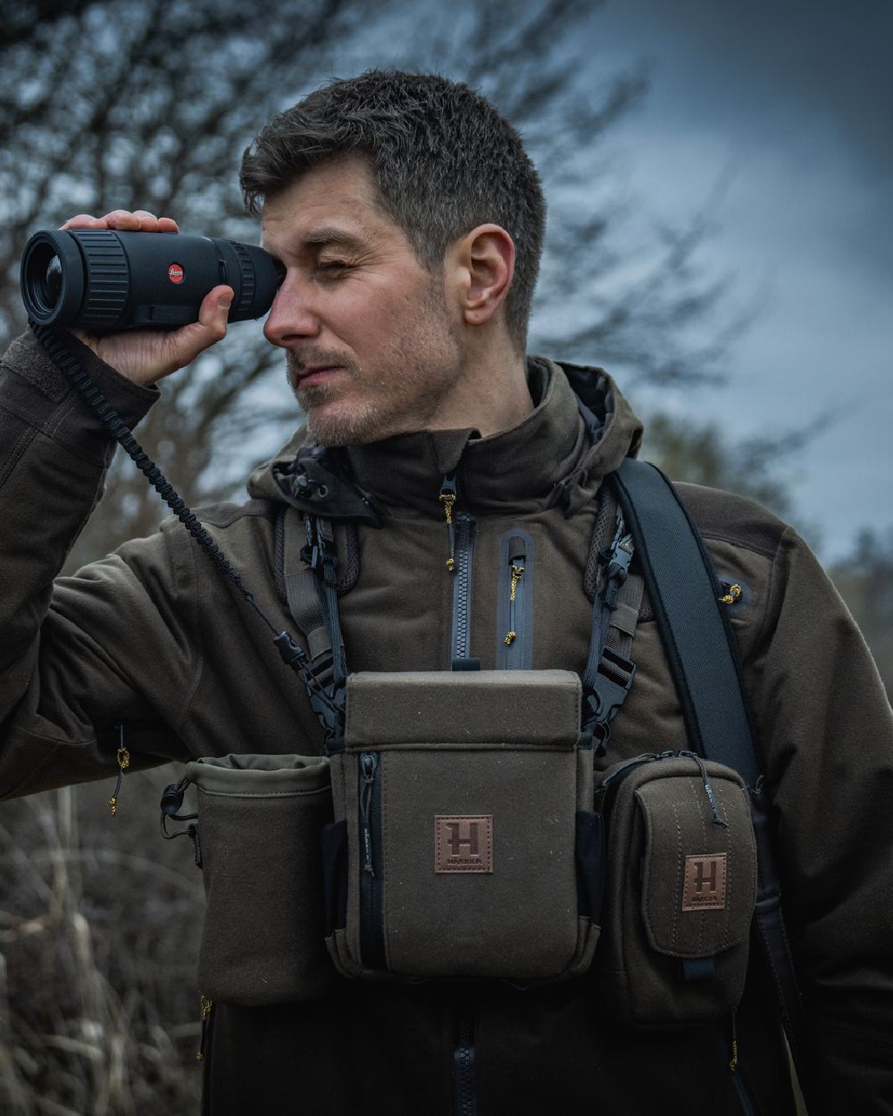 Dark Willow Green Coloured Harkila Thermal Spotter Pouch on blurry background