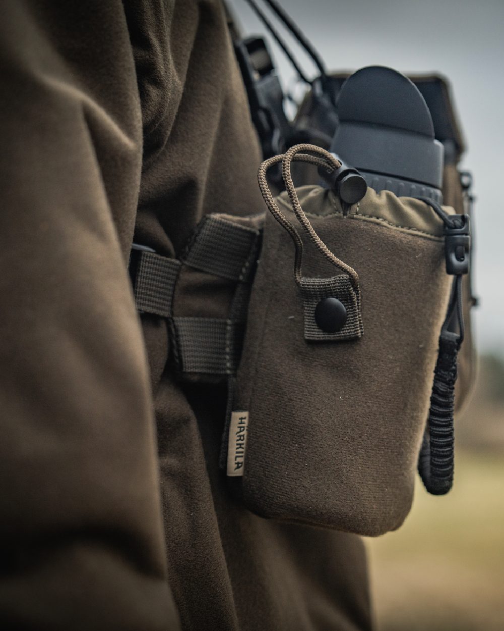 Dark Willow Green Coloured Harkila Thermal Spotter Pouch on blurry background