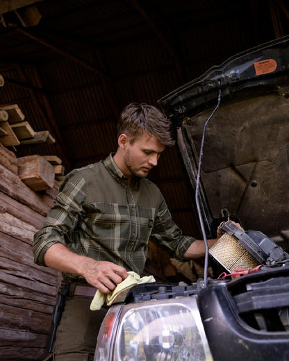 Willow Green coloured Harkila Anker Long Sleeve Shirt worn by man working on an engine in a farm