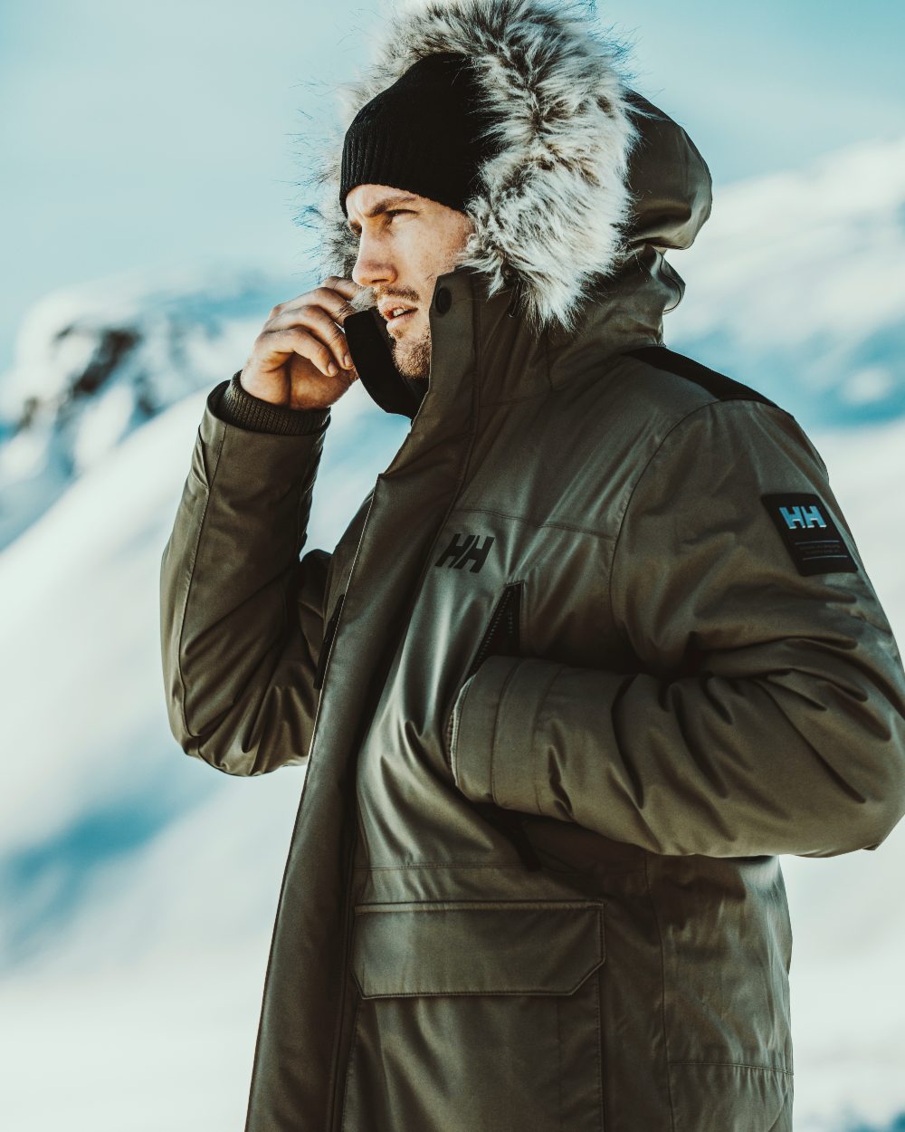 Utility Green coloured Helly Hansen Mens Reine Winter Parka on snow background