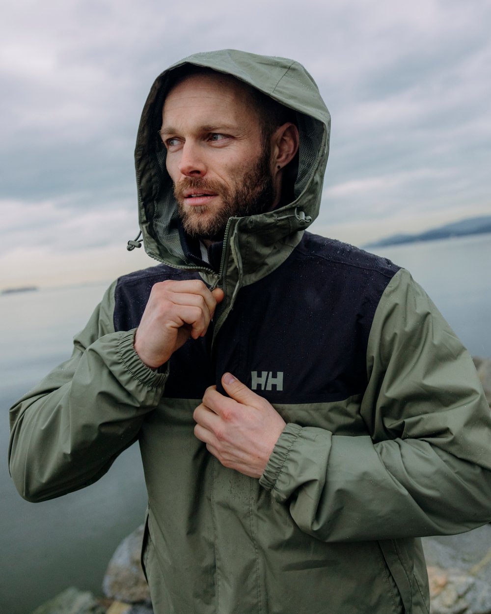 Lav Green coloured Helly Hansen Mens Vancouver Rain Jacket on blurry background
