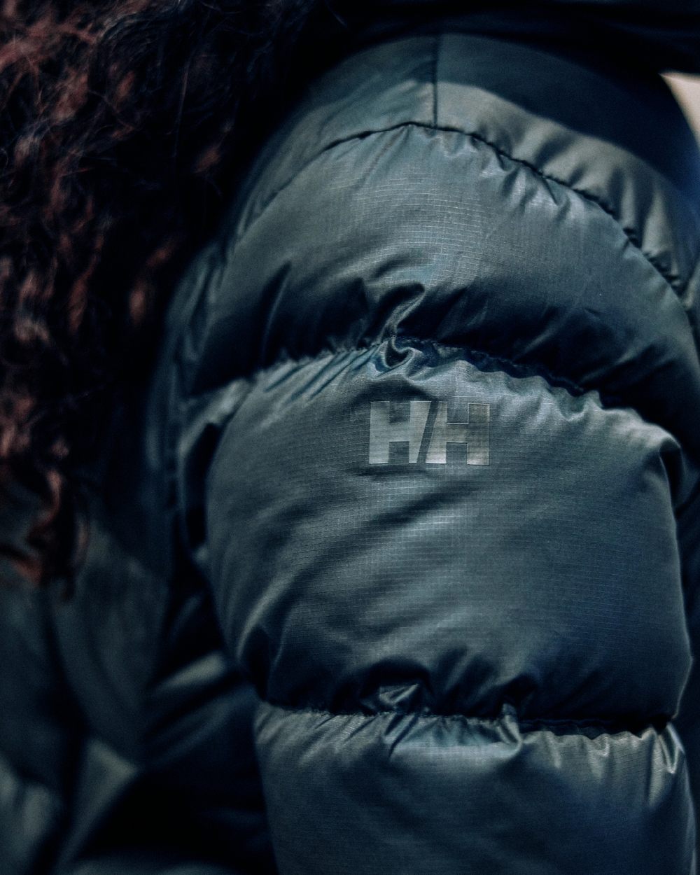 Black Coloured Helly Hansen Womens Essence Down Jacket on blurry background